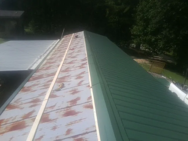 Old rusted panels beside newly installed green metal roofing — Wind Damage Roof Repair by Roofing Brothers in Ennis