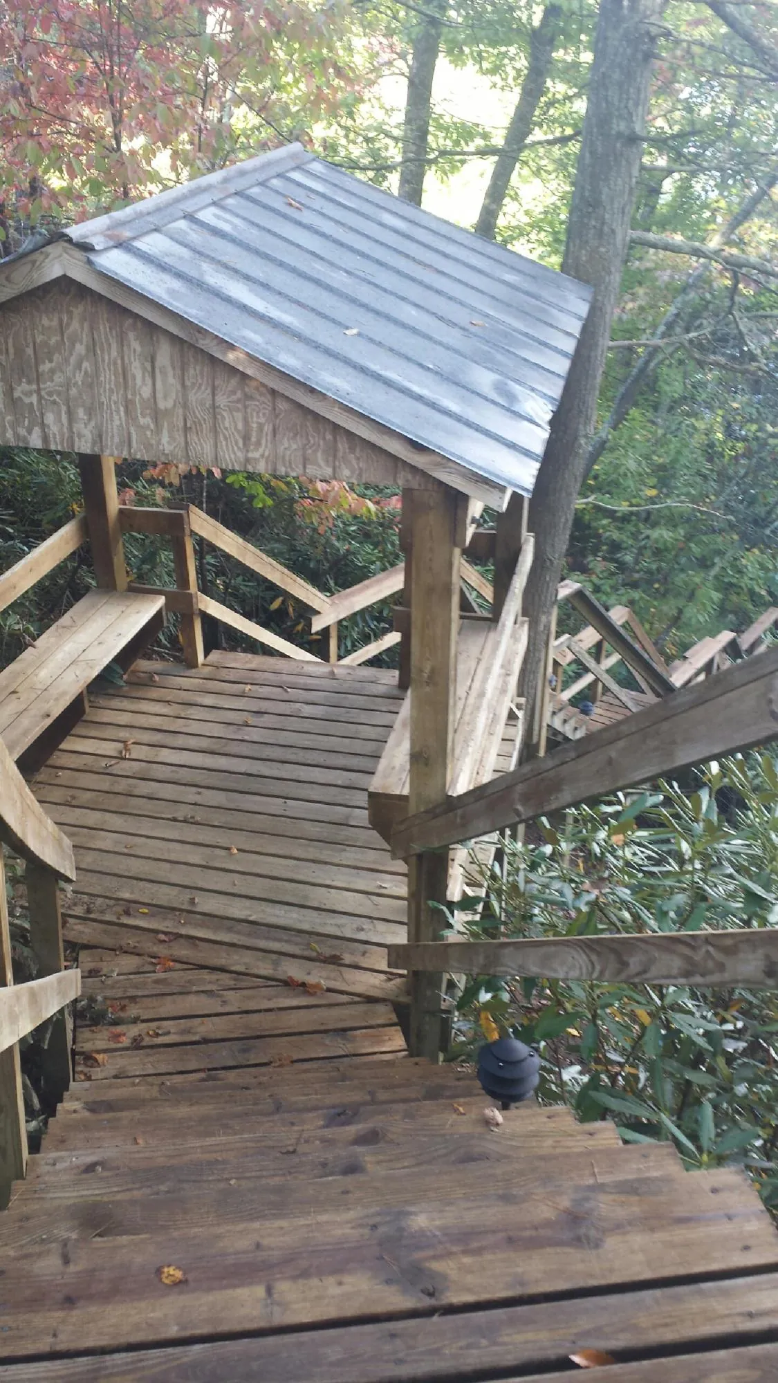 Metal roofed shelter over wooden steps on a wooded walkway — Skylight Repair & Installation work by our crew in Ennis